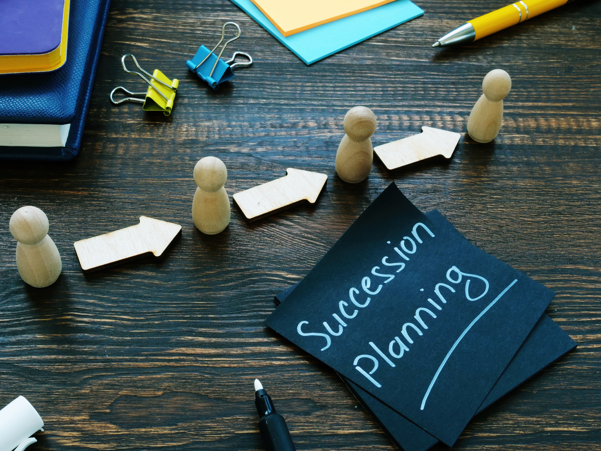 Wooden blocks and paper on a desk depict the concept of business succession planning, ensuring smooth transitions.