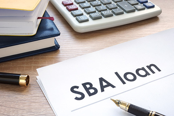 Close-up view of a document titled 'SBA loan' with a calculator and fountain pen, symbolizing venture financing and financial planning for maximizing SBA loan benefits