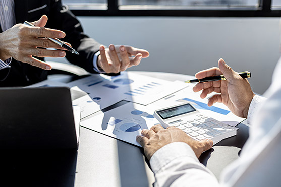 Business professionals discussing venture financing with charts and calculator on table during a meeting in a bright office environment